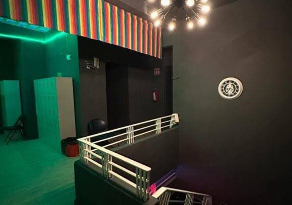 Interior del club con columnas clásicas y piso de mármol reflejando luz neón violeta